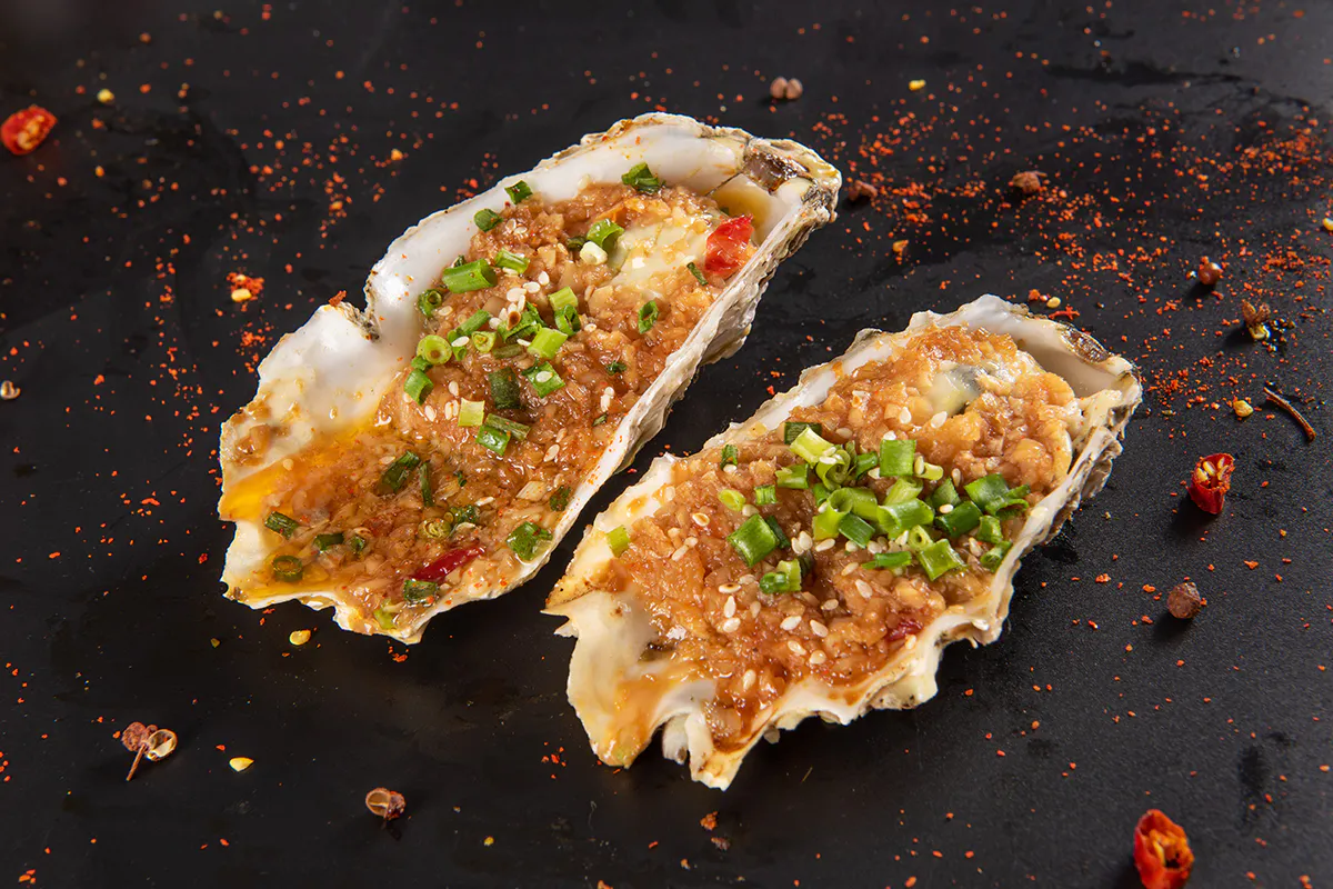 Grilled oysters topped with garlic scallions and sesame at Aquaman BBQ, a Barbecue Restaurant in Queens